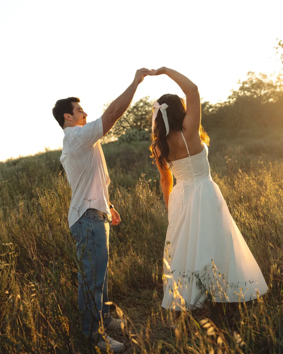 He twirls her under his arm beneath a tree, the low sun behind them